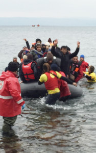 Volunteers rush into the water to help refugees land in Lesvos. Turkey can be seen in the background. 