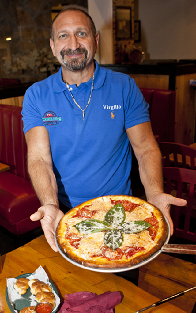 Owner Virgilio Urbano shows off a pie at Virgilio’s Pizzeria in Littleton. 