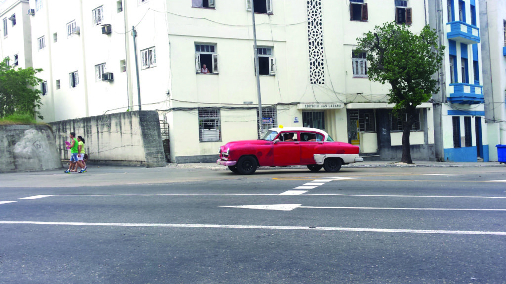 A classic car cruises in front of la Universidad de La Habana.