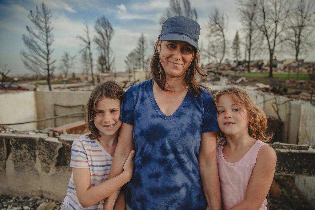 The Szucs family in front of their destroyed home as a result of the Marshall Fire.