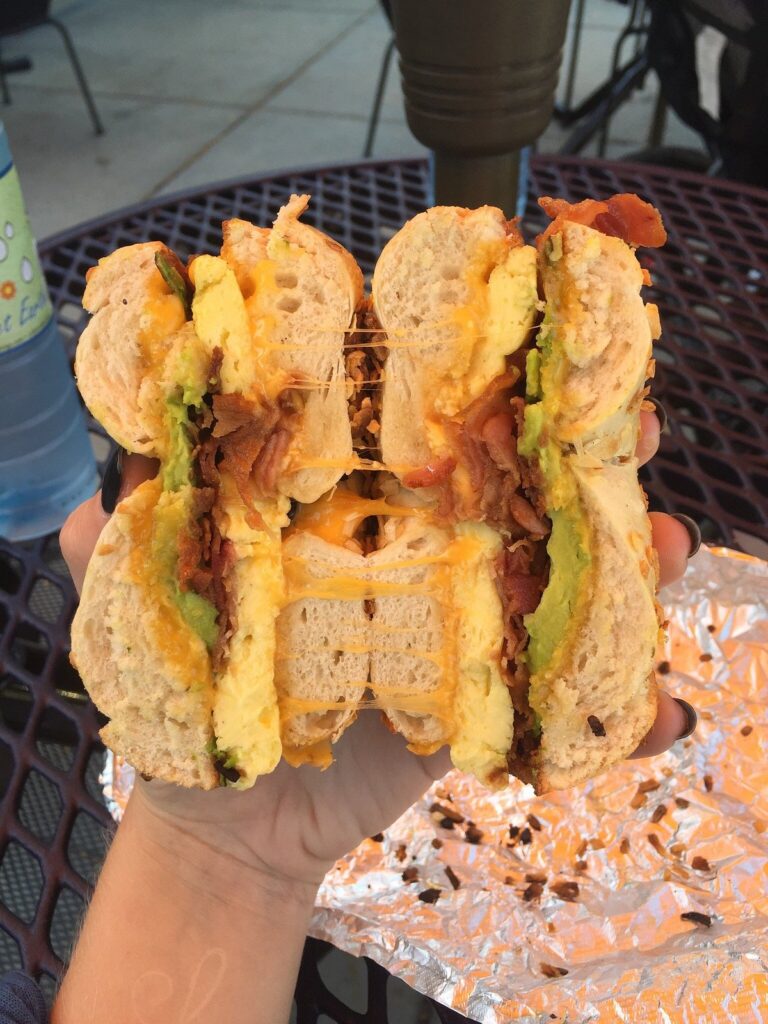 bagel sandwich in hand with egg bacon guacamole from Moe's Broadway Bagel in Boulder