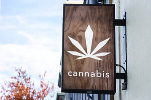 A cannabis dispensary sign with a large marijuana leaf on it