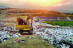 Dig on the garbage Solid waste management bulldozer at landfill with sun and trash