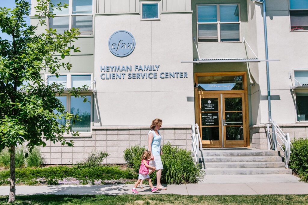 woman and child walking in front of EFAA offices in Boulder, Colorado on sunny day with green tree