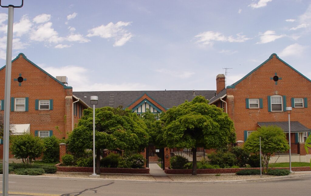 brick building with two peaked facades The Inn Between in Longmont trees blue sky clouds affordable nonprofit housing